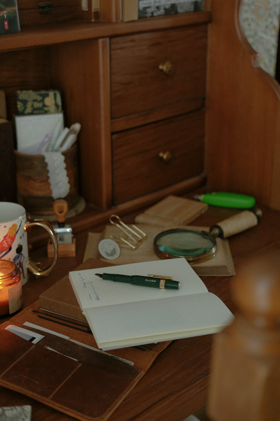 Houten bureau met open notitieboek, pen en schrijfaccessoires.